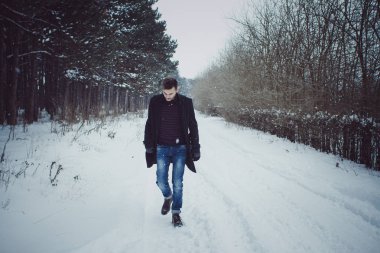 Kar fırtınası sırasında ormanda yürüyen genç adam portresi