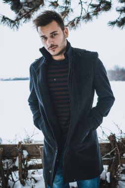 Kışın kar kucaklayan genç çekici bir adam. Portre portre