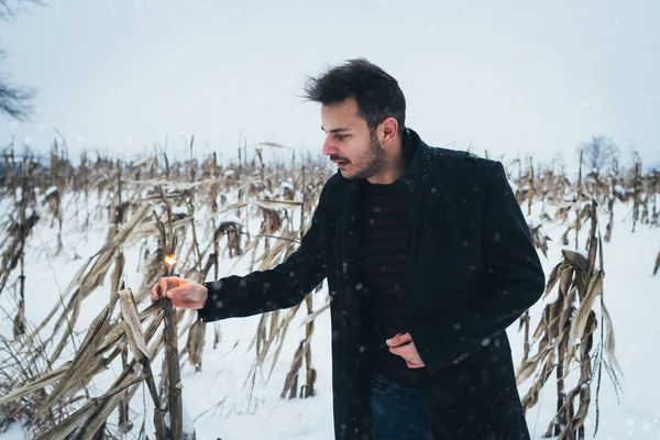 Young man in corn field standing with sparkles  in the snow