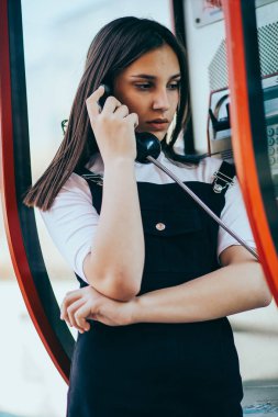 Çekici bir kadın telefon kulübesi üzerinden genel bir telefon görüşmesi