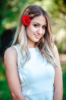 Yakın, genç güzel sarışın kız portresi Saçında kırmızı gül ile 