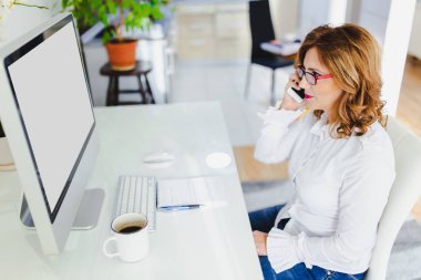 Kadın telefonda konuşurken ve modern ofis gazetelerde bakarak