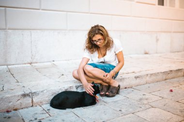 Kadın sokakta bir kedi ile oynarken