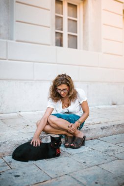 Kadın sokakta bir kedi ile oynarken
