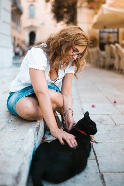 Kadın sokakta bir kedi ile oynarken
