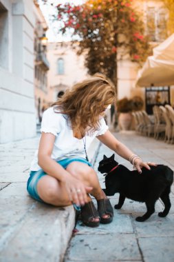Kadın sokakta bir kedi ile oynarken