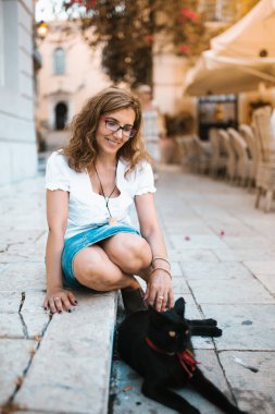Kadın sokakta bir kedi ile oynarken