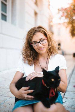 Kadın sokakta bir kedi ile oynarken