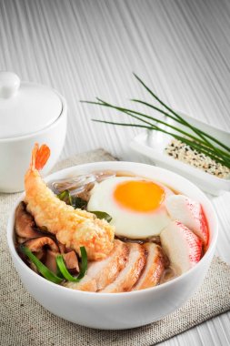 Beyaz tabakta yumurta ile deniz ürünleri çorbası.