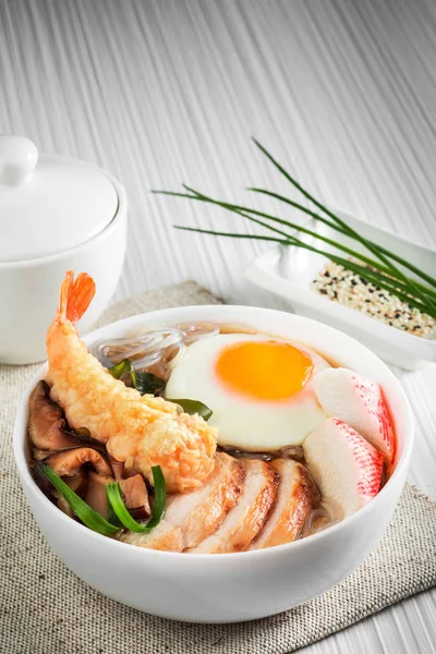 Beyaz tabakta yumurta ile deniz ürünleri çorbası.