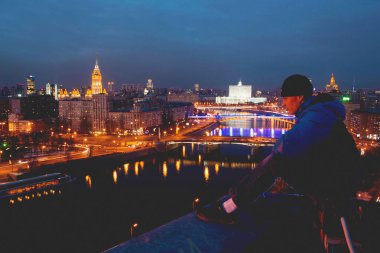 Çatıda bir adam poz veriyor. Şehir fotoğrafına bakıyor. Moskova, 2016-2017 sonbaharında, gökyüzü, şehir, adam.