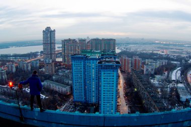 Çatıda bir adam poz veriyor. Şehir fotoğrafına bakıyor. Moskova, 2016-2017 sonbaharında, gökyüzü, şehir, adam.