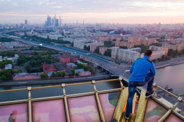 Çatıda bir adam poz veriyor. Şehir fotoğrafına bakıyor. Moskova, 2016-2017 sonbaharında, gökyüzü, şehir, adam.