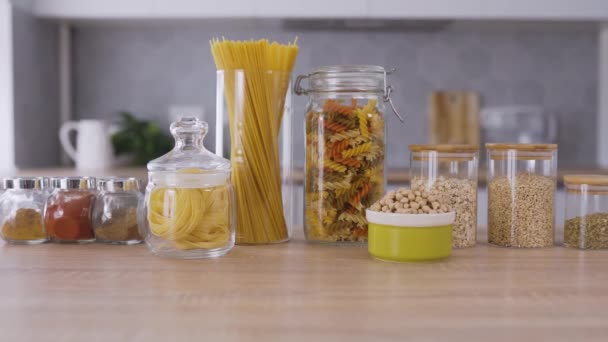 Tészta és fűszerek az asztalon lévő üvegekben — Stock videók
