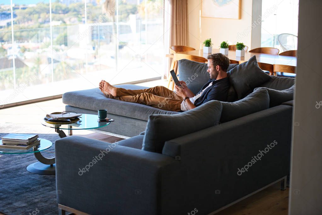 modern man lazing on the couch of a luxurious apartment