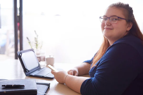 Chubby woman looking at camera while seated in a cafe — Stock Photo, Image