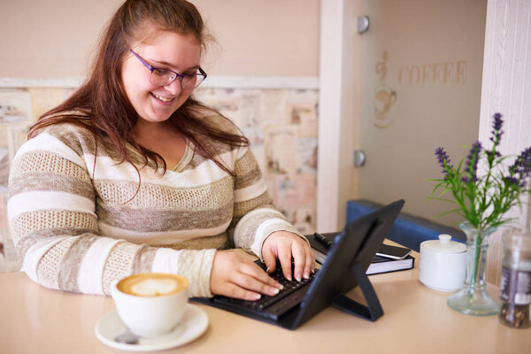 Plus size woman smiling while working in a bright cafe