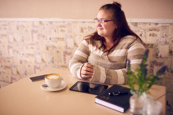 beautiful obese caucasian woman in cafe looking into window light