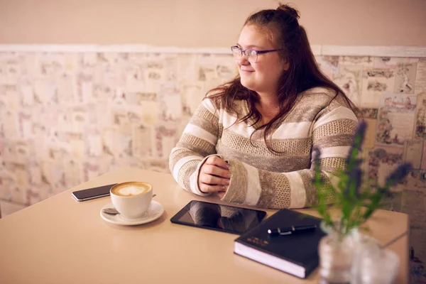 Beautiful obese caucasian woman in cafe looking into window light Stock Photo