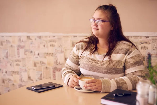Übergewichtige Frau hält eine Tasse Kaffee in einem Café lizenzfreie Stockbilder