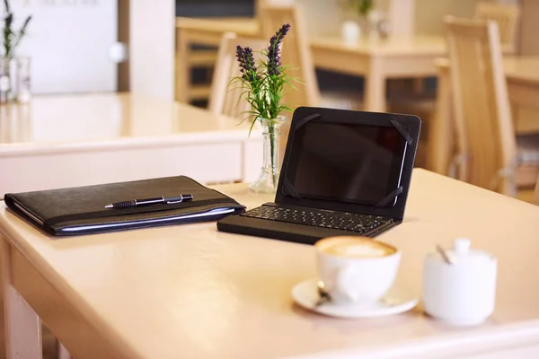 Tisch im Café mit elektronischem Tablet und Kaffee Stockbild