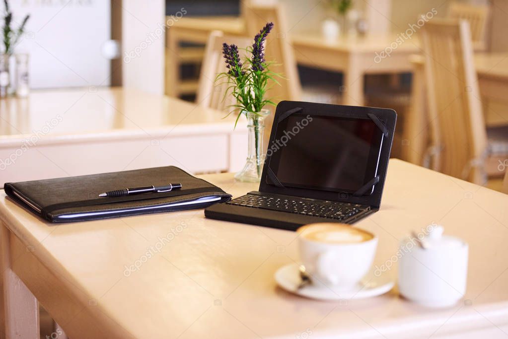 Table in a cafe with an electronic tablet and coffee