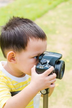 DSLR kamera ve tripodlarla doğada fotoğraf çeken Asyalı çocuk.