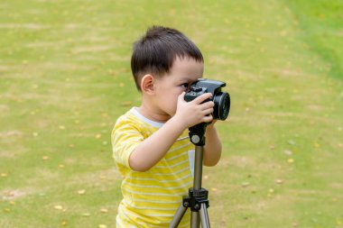 DSLR kamera ve tripodlarla doğada fotoğraf çeken Asyalı çocuk.