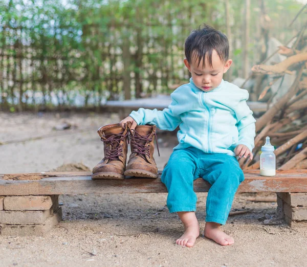 Asiatischer Junge Versucht Vater Stiefel Tragen Während Milch Aus Flasche — Stockfoto