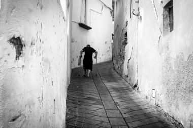 Stromboli (Messina), İtalya - 25 Ağustos 2020: Yaşlı bir kadın Aeolian takımadalarında (Sicilya) volkanik bir ada olan Stromboli adasında dik bir sokağa tırmanır. Fotoğraf halka açık bir yerde çekildi..