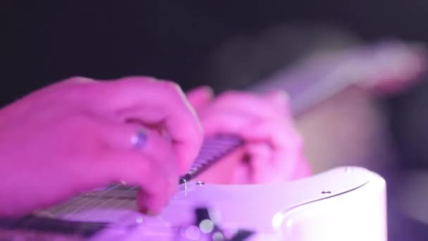 Les mains de guitariste macro gros plan des doigts arrachant des cordes de guitare électrique jouant au ralenti néon boîte de nuit lumière. Musicien homme exécute solo pressage accords concert inspiration répétition groupe 