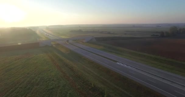 パンの航空写真道路交差点フィールド交通輸送運転を朝風景 田舎橋のローカル道路のジャンクションでの高速道路経由便 輸送物流貨物 — ストック動画