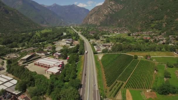 垂直トラッキング ビデオ撮影 緑の山間の谷の高速道路町住宅畑ズームアウト ドローンです ヨーロッパ村 車線道路の の空中パン ビュー 貨物運輸物流旅行 — ストック動画