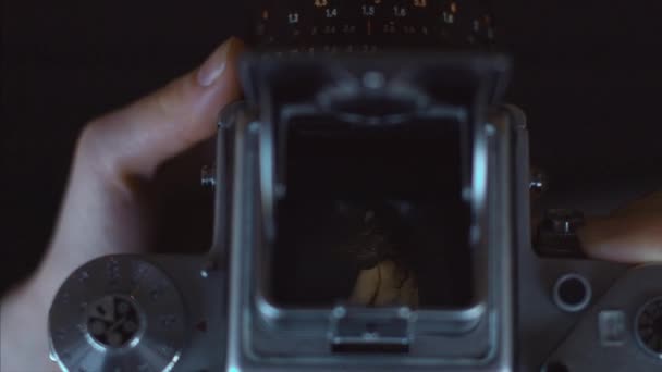 女性手紧紧地拿着老式的相机拍摄聚焦女孩在室内 年轻女子在取景器中为摄影师摆姿势的黑暗视频拍摄 记忆遗产女性美丽 — 图库视频影像