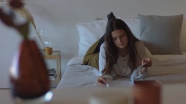 Yatak odası iç yaşam tarzı portre 4k kağıt kitap okuma Çekici kadın. Zarif kız yatakta dergi tutarak yalan kapalı doğal ışık alay. Kadın moda stili tasarımcı giysi cilt bakımı