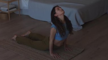 Konsantre kadın ev iç 4k sabah ışığında spor fitness egzersiz yapıyor germe. Güzel kız tek başına kapalı vinyasa yoga pratik. Relax zihin özgürlüğü kendini tanıma geliştirme