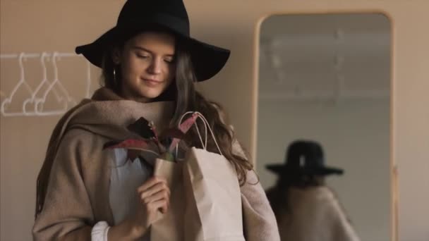 4Kショッピングの前に屋内でポーズ紙袋をモックアップファッショナブルな女の子 反射幸せな感情を映し出すために見て ボショースタイルの若い女性 エコロジートレンドファッション業界 — ストック動画