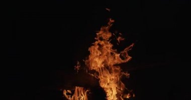 Geceleri karanlık arka planda yanan parlak kamp ateşi. Turuncu alev yakın parıltılar siyah kopya alanı yavaş hareket açık havada hareket ediyor. Yaz eğlenceli faaliyetleri yangın tehlike orman koruma kamp