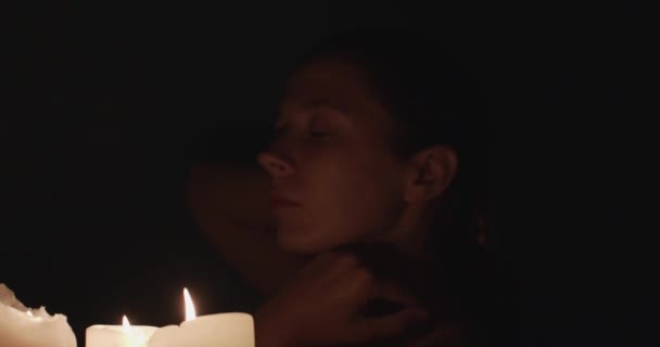 キャンドルライトで夜風呂に入る女性 穏やかな若い女の子は 閉じた目でリラックスロマンチックな雰囲気官能的な肌のタッチをお楽しみください リラクゼーション瞑想コンセプト — ストック動画