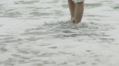 Çıplak kadın ayakları düşük açı görünümü deniz dalgalarının beyaz köpük adım açık havada yavaş hareket. Tanınmayan kadın okyanus suyu kumlu sahilde duran iyi vakit tatil tatil hiçbir yüz harcama