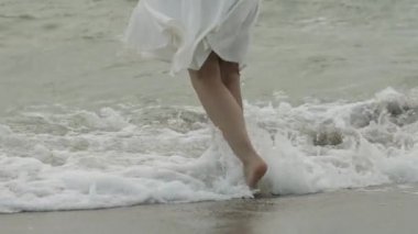 Deniz okyanusunun yavaş hareketinin sulara basan yüzsüz kadının arka görünümü. Kadın bacaklar yalınayak yakın beyaz köpük dalgalar deniz manzara arka plan ayakta kadar. Yaz tatili mutluluğu