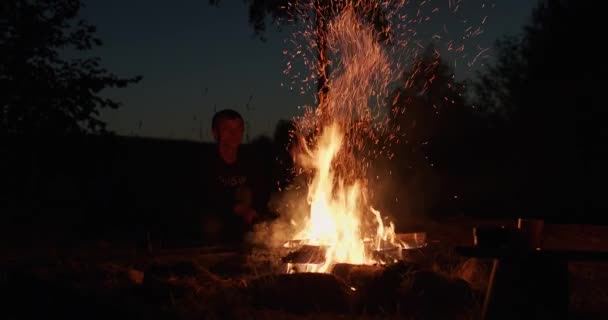 着迷的人移动木材在火户外 徒步旅行者使篝火放松在夜间单独自然背景慢动作手持相机 童子军露营徒步旅行夏季休闲活动 — 图库视频影像