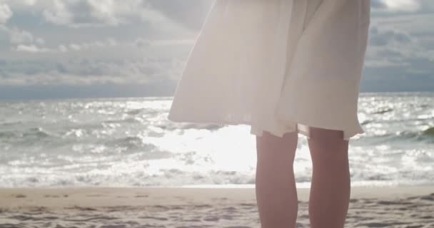 无脸的女人独自站在海边看海水表面梦想幸福特写 女性腿在白色裙子颤抖在夏天的风自然阳光 夏季旅行假期 — 图库视频影像