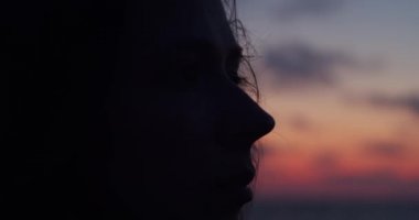 Renkli gökyüzü arka plan üzerinde günbatımı akşam ışığı ile siluetli kadın yüz yan görünümü kadar yakın. Açık havada bir kenara bakan genç kadının makro portre kopya alanı. Duygu sorunu depresyon kavramı