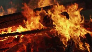 Large Bonfire With Logs And Coals Burns Brightly Outdoor Close-up Slow Motion Video. Burning Logs In Beautiful Colorful Orange Flames With Hot Heated Coal Shimmering Red Glow. Burning Process