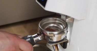 Barista kahve makinası için Portafilter 'a öğütülmüş kahve hazırlıyor. Elektrikli Öğütücü kahve çekirdeğini filtre tutacağına öğüttü. Kafede baştan sona kahve yapan profesyonel kahve makinesi.