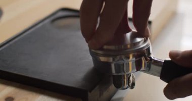 Profesyonel barista, taptaze kahve çekirdekleri ile öğütülmüş kahve yapıyor. Barista 'nın elleri kahveyi taze öğütülmüş kahveye bastırmak için kurcalayıcı kullanıyor. Kahvede baştan sona kahve yapıyor.