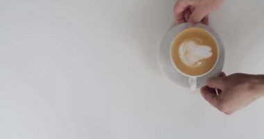 Yüzsüz garsonun kafede doğal ışık altında kadınlara cappuccino servis edişinin en üst görüntüsü. Erkek eller beyaz bardağı masaya koyar ve kız ağır çekimde alır. Restoran sokak yemekleri yaşam tarzı