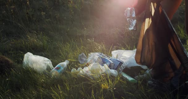 顔のない女性のごみ箱袋に屋外の自然林の背景に遅い動きを収集します 日没に公園で緑の芝生のゴミを取っている女性の手 生態環境 地球環境汚染 — ストック動画