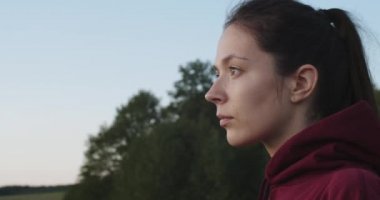 Çekici bir kadın açık havaya bakıyor ve doğa hakkında bir şeyler düşünüyor. Ağaçların orada poz veren doğal makyajlı bir kız. Yavaş çekim el kamerası. Yüz estetiği cilt bakımı 4K